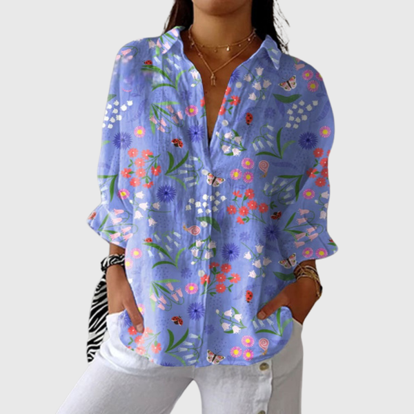 Lichtgewicht damesblouse met kleurrijke print en ruime snit, gedragen op een nette pantalon