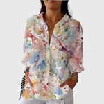 Vrolijke damesblouse met luchtige print in warme kleuren, gedragen bij een spijkerbroek